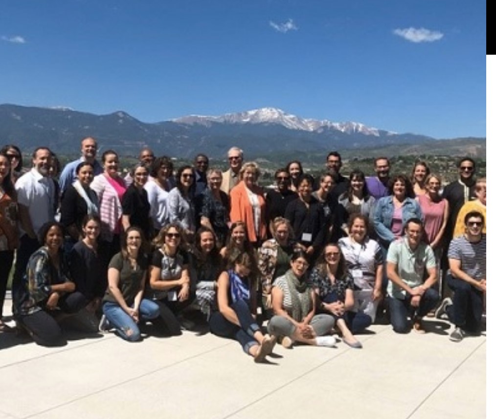 people posing for group photo in front of mountain