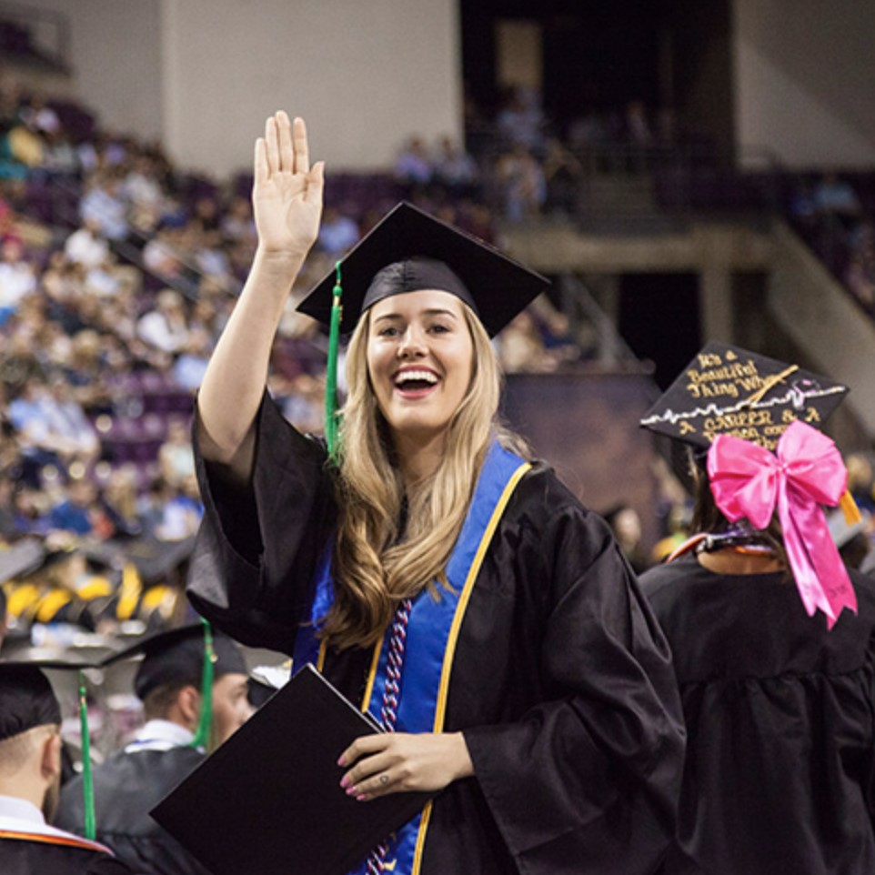 Student in graduation robes smiling at camera