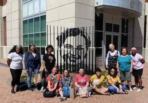 Group of students stand in front of a Rosa Parks Mural 