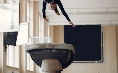 Child gymnast doing flip above a balance beam